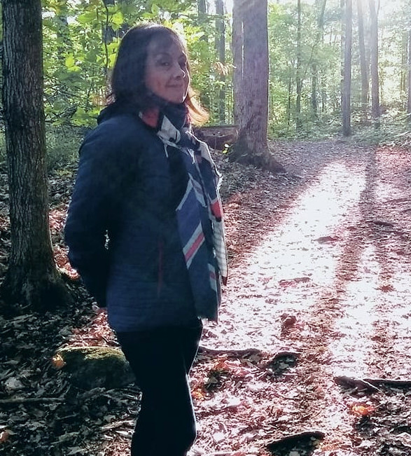 Liliana Diaz standing in woods with light through trees