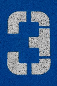 The number 3 in white stencil on a textured blue surface